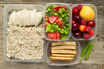 Healthy food, cooked in containers, pearl barley porridge with chicken breast, vegetables, fruits.