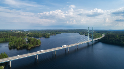 Aerial view of modern bridge with cars across blue lake at summer time. Beautiful sky with clouds....