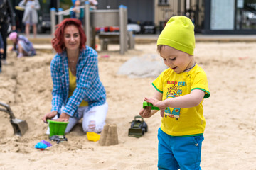 young grandmother playing with her little grandson two years old on the playground outside in the...