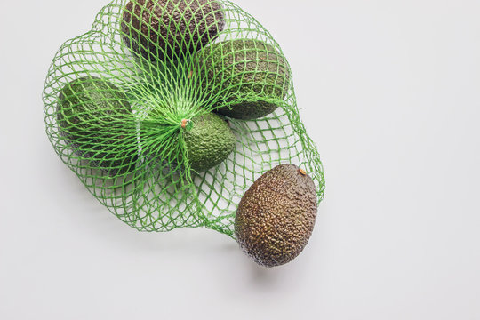 organic avocado in mesh bag flat lay on white background 