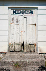 Worn, white wooden door on an abandoned house.