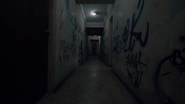 Old Apartment,Ghetto Building,long Dark Hallway.Tracking inside a dark long hallway of a ghetto apartment complex.Graffiti vandalism and abandonment in a poverty stricken neighbourhood.