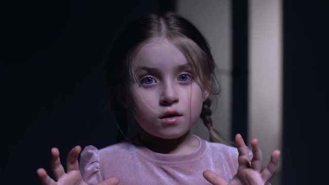 Little female child suddenly scared on camera, afraid of darkness, ghosts phobia