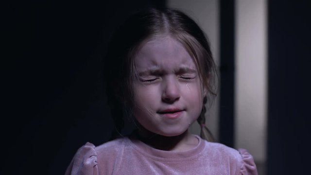 Scared little girl crying and closing eyes from fear, childhood phobias, closeup