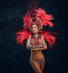 Happy beautiful brasil dancer in red feather costume is dancing on small scene.