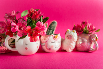 Obraz na płótnie Canvas Unicorn mugs and Flamingo mug with Alstroemeria on bright pink background. Idea of Girly settings. Vivid postcard for any holidays