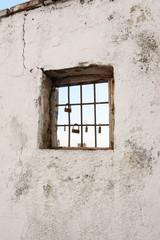 The sky seen through the window with bars of a ruined house