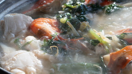 Boiling seafood soup with shrimps, crabs, clams and vegetables cooked in Jagalchi fish market in South Korea in Busan.