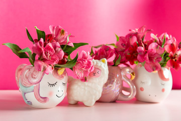 Unicorn and Flamingo mugs with Alstroemeria on bright pink background. Idea of Girly settings. Vivid postcard for any holidays