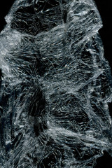 Transparent plastic wrap on the black background. Plastic bag texture. Reusable trash and waste.
