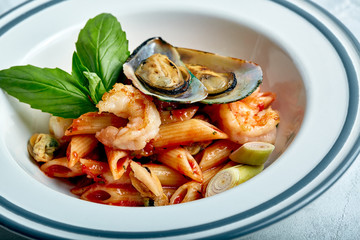 Pasta with seafood and tomato sauce. Penne with shrimp, octopus, mussels, Vongli in tomato sauce with basil