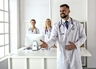 Welcome. Smiling doctor greets a patient by handshake. Male practitioner in white uniform. Female physicians. Greeting in medical office. Reception. Healthcare. Treatment. Medicine.