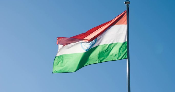 State Flag of India. The Big State Flag is illuminated by the sun and flutters epically in the wind against the blue sky. Slow Motion 120 fps
