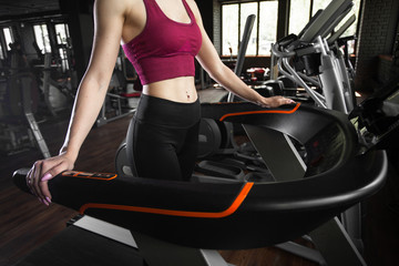 Fototapeta na wymiar Young pretty woman running on treadmill. Loft interior of modern fitness club in black colour. Concept of health and sport lifestyle. Athletic Body.