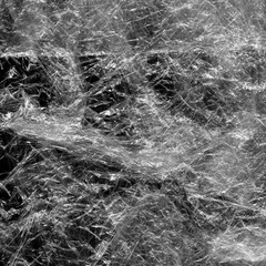 Transparent plastic wrap on the black background. Plastic bag texture. Reusable trash and waste.