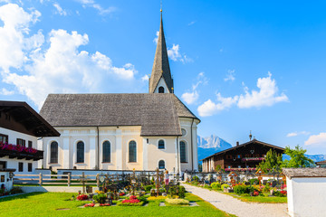 Fototapeta na wymiar Beautiful church and cemetery near Kitzbuhel town and view of alpine houses, Tirol, Austria