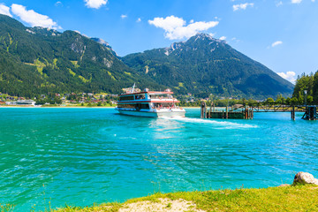Tourist ship sailing out from pier on shore of Achensee lake on sunny summer day, Pertisau, Tirol,...
