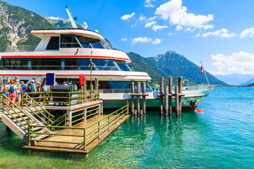 Tourists waiting to enter ship mooring at pier on shore of Achensee lake on sunny summer day, Pertisau, Tirol, Austria