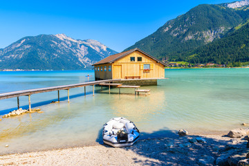 Wooden boat house and pier of shore of beautiful Achensee lake on sunny summer day, Tirol, Austria