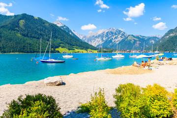 Sailing boats and view of beach near Pertisau town at beautiful Achensee lake on sunny summer day, Tirol, Austria
