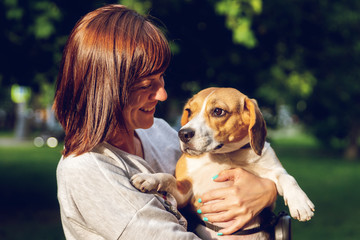 Girl holding a dog in her arms on the nature background at summer time. Lifestyle photo.