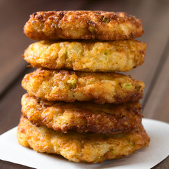 Rice patties or fritters made of cooked rice, carrot, onion, garlic and celery stalks arranged in a pile, photographed with natural light (Selective Focus, Focus on the front of the patties)