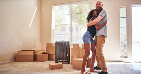 happy interracial couple embracing after moving into new house