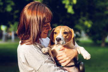 Girl holding a dog in her arms on the nature background at summer time. Lifestyle photo.