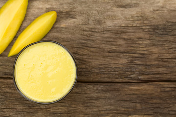 Frischer Smoothie aus Mango und Joghurt im Glas, fotografiert auf Holz mit Textfreiraum an der...