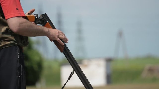 Sportsman breaking the double-barrel gun and reloading it on a range in slo-mo  