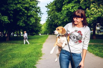 Girl holding a dog in her arms on the nature background at summer time. Lifestyle photo.