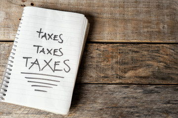 taxes word written with black marker on notebook