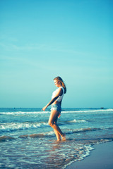 Fototapeta na wymiar young pretty blond woman at seacoast walking relaxing, fashion lady at sunset, cool vacations