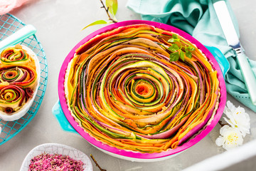 Spiral vegetable tart on colorful decorated table.