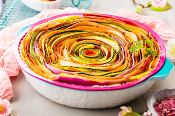 Spiral vegetable tart on colorful decorated table.