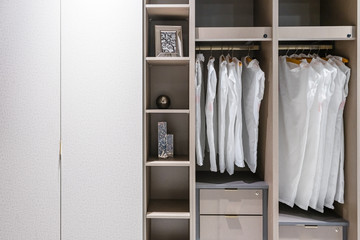 modern wooden wardrobe with women clothes hanging on rail in walk in closet, Scandinavian style