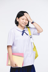 Cute girl in student's uniform with stationery on gray background.