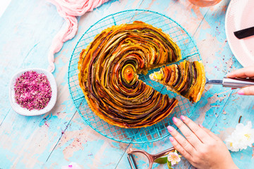 Spiral vegetable tart on colorful decorated table.