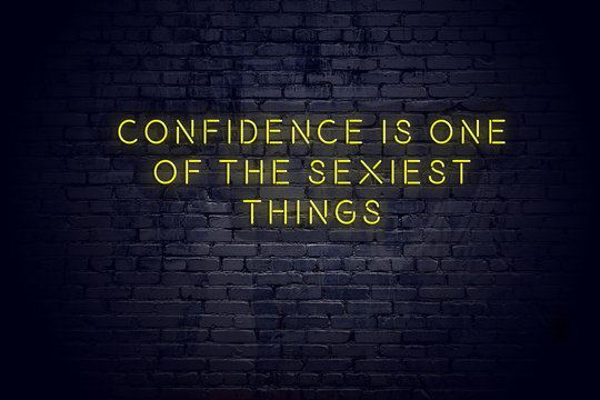 Neon sign with positive wise motivational quote against brick wall 