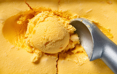 top view mango flavor ice cream ball and spoon close up