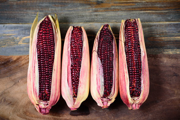 Fresh purple sweet corn on wooden background, top view