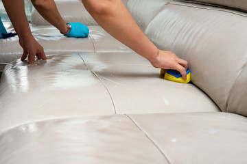 ladies cleaning leather sofa with soapy sponge