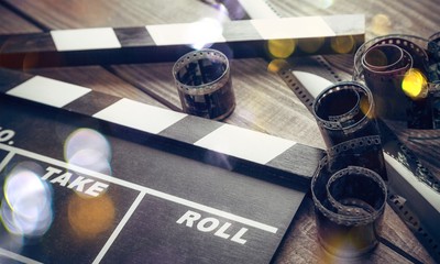 Movie clapper board and film tapes on wooden background