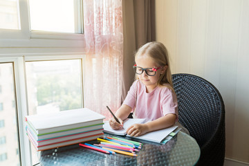 Cute little caucasian girl doing homework and writing a paper. Kid enjoy learning with happiness at home. Clever,Education and smart learning concept