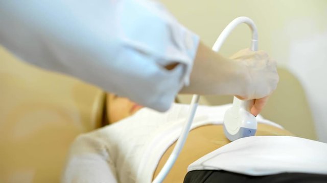 Ultrasonic in modern clinic. A close up the hand of the doctor Taking A Sonogram a stomach the woman in slow-mo