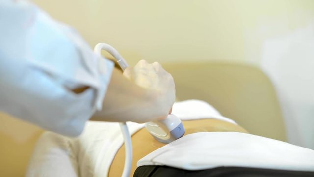 the hand of the doctor Taking A Sonogram a stomach the woman