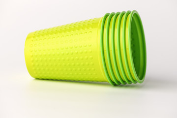 A group of green plastic cups lie on a white background. The cups are a doll.