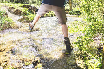 Male legs, in waterproof sports hiking boots, walking on water(river)