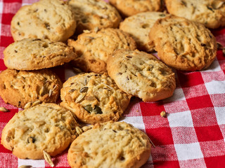 Oatmeal cookies with husk unpeeled oats on kitchen gingham checkered cotton fabric on table in farm-style.