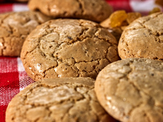 Oatmeal cookies with crack pattern on red kitchen gingham checkered cotton fabric on table in farm-style.